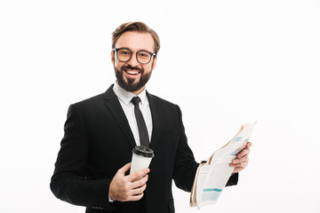 Poster - Portrait of cheerful male employer in suit and eyeglasses smiling while drinking takeaway coffee and reading newspaper, isolated over white wall