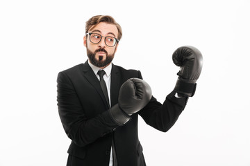 Wall Mural - Portrait of courageous business man in suit and eyeglasses boxing in black gloves, isolated over white background