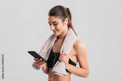 Αφίσα Portrait of young woman in gym posing with towel on neck and listening to music