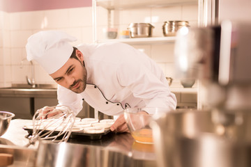 Wall Mural - confectioner checking dough in baking forms in restaurant kitchen