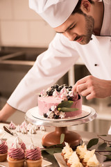 Wall Mural - portrait of confectioner decorating cake in restaurant kitchen