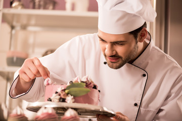 Wall Mural - portrait of confectioner decorating cake in restaurant kitchen