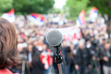 Wall Mural - Political protest. Demonstration. Microphone in focus against blurred crowd.