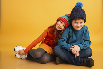 Wall Mural - Two happy little children wearing warm hats.