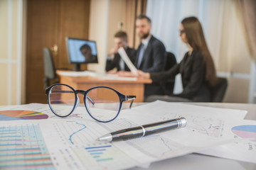 Wall Mural - financial chart near dollars seen by unfocused glasses ( colleagues meeting to discuss their future financial plans only silhouettes being viewed )