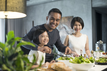 Happy Asian family preparing food in the kitchen.