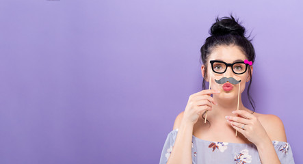 Wall Mural - Young woman holding paper party sticks on a solid background