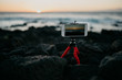 Mobile phone on the tripod shooting the sunset on the rocky shore of the ocean
