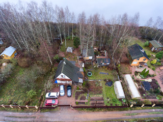 Wall Mural - Timber house with courtyard, barns and small garden is on lake shore. Aerial view at spring season. Russia