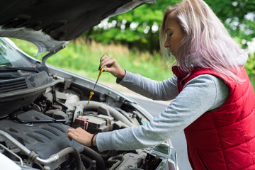 Wall Mural - Girl checks the oil in the car's engine