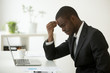 © fizkes - Headache at work concept, stressed african-american businessman feels strong sudden migraine working on laptop at workplace, frustrated dizzy black man in suit touching head tired of chronic fatigue