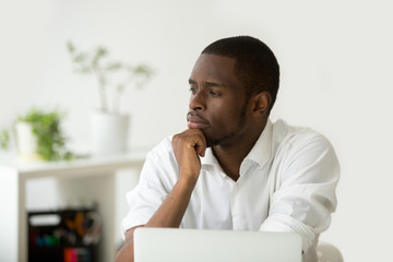 young african-american thoughtful businessman holding hand on chin planning future project at work w