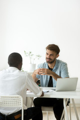 Canvas Print - Two diverse young businessmen talking discussing new project idea, caucasian hr holding job interview with african candidate, multiracial colleagues working together in office teamwork, vertical view