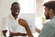 © fizkes - Caucasian advisor consulting african american client about loan, mortgage or insurance showing financial statistics, white adviser talking to black smiling businessman about new project investment