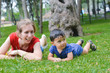 © sashasandro - Happy biracial family in the summer park - caucasian mother with her latin son laying on the grass.