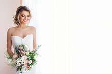 Portrait Of A Beautiful Bride With A Wedding Bouquet. Blonde Girl With Curly Hair And Fashion Makeup.
