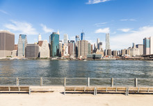 The Famous Riverside Promenade In Brooklyn With The Manhattan Business District In The Background Across The East River In New York City On A Sunny Day In The USA