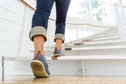 Fotografía Young adult woman walking up the stairs with sun sport background