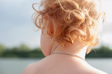 Wall Mural - Children's red curls on the background of the river