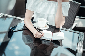 Wall Mural - Taking notes. Close up of a notebook being on the table while being used for taking notes by a nice young woman