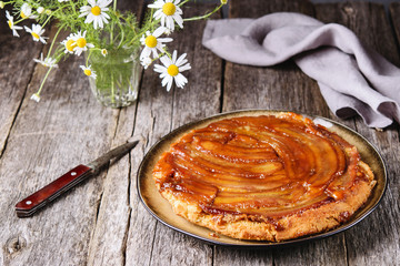 Wall Mural - Traditional homemade banana caramel pie on vintage wooden table decorated a bouquet of chamomiles. Upside down banana cake. Selective focus 