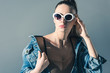 © LIGHTFIELD STUDIOS - fashionable girl posing in denim clothes and sunglasses, isolated on grey