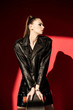 © LIGHTFIELD STUDIOS - attractive stylish girl in black leather jacket posing with skateboard, on red