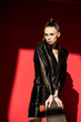 © LIGHTFIELD STUDIOS - attractive young woman in black leather jacket posing with skateboard, on red