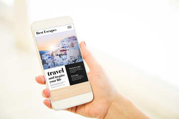 Canvas Print - Woman holding a pink gold blank smartphone showing  travel website