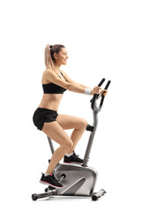 Wall Mural - Young woman exercising on a cross trainer machine