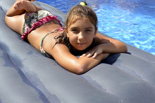 Portrait Of A Girl In Bikini Sunbathing On An Inflatable Mattress In Swimming  Pool