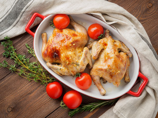 two carcasses fried chicken in a bowl, baked chucks in an oven with tomatoes, with crispy crust, on  dark brown wooden rustic table, top view