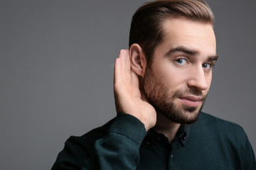 Wall Mural - Young man with hearing problem on grey background