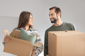 Poster - Young couple with moving boxes on gray background