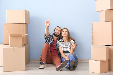 Poster - Young couple with moving boxes on floor in room