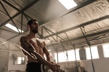 Wall Mural - Muscular man exercising with heavy rope at gym