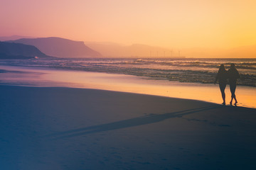 couple walking in the beach at the sunset