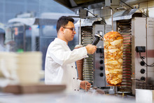Chef Slicing Doner Meat From Spit At Kebab Shop
