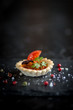 tomato tartelette with fresh tomato slice and olive and fresh herbs