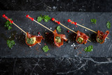 Fototapeta Boho - parma ham and cheese skewers with olive oil on black plate with salt and peppercorns