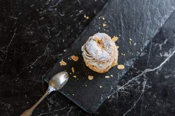 Wall Mural - Paris Brest french cream cake pastry isolated on black plate sprinkled with almonds 