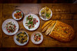 top view of assorted dishes and mezze in mediterranean restaurant  with focaccia bread on wooden table 