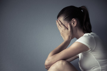 Portrait of sad woman sitting in a dark room. 