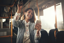 Young Woman Laughing While Listening To Music On A Bus