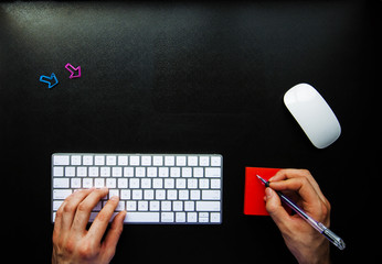 Noting while using keyboard on black desk with copy space