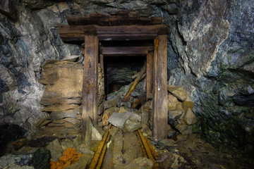 Underground abandoned gold ore mine shaft tunnel gallery with wooden timbering