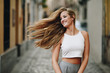 © javiindy - Happy young woman with moving hair in urban background.