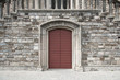 Burgundy door in stone wall with elaborate frame