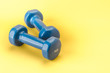 blue dumbbells on a yellow background/blue dumbbells on a yellow background. Copy space