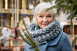 © Yakobchuk Olena - Portrait of cheerful mature woman standing near fir-tree on street. She is looking at camera and smiling